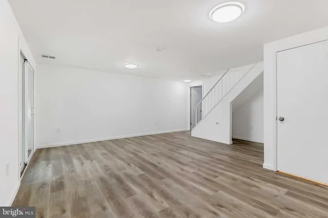 a view of an empty room with wooden floor and stairs