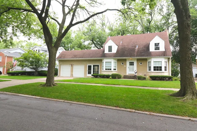 a front view of a house with a garden and trees