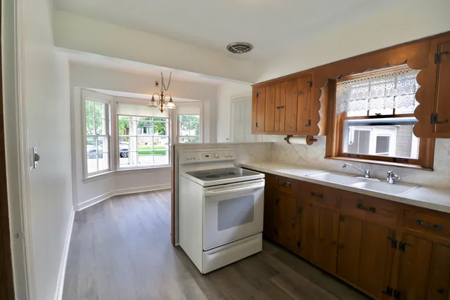 a kitchen with stainless steel appliances granite countertop a stove a sink dishwasher a refrigerator with wooden cabinets and wooden floor