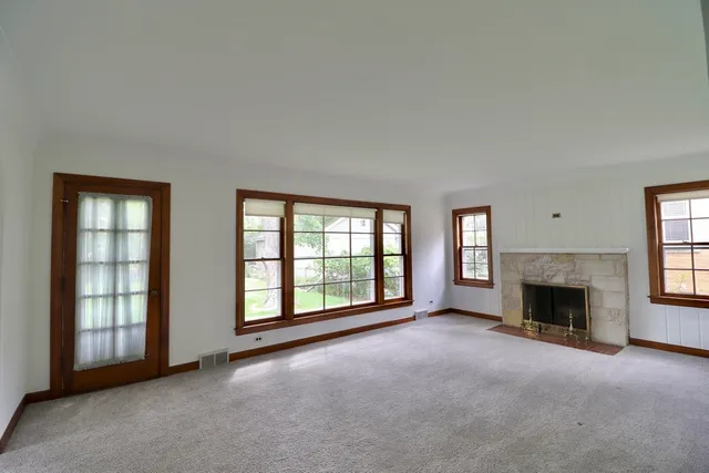 an empty room with windows and fireplace