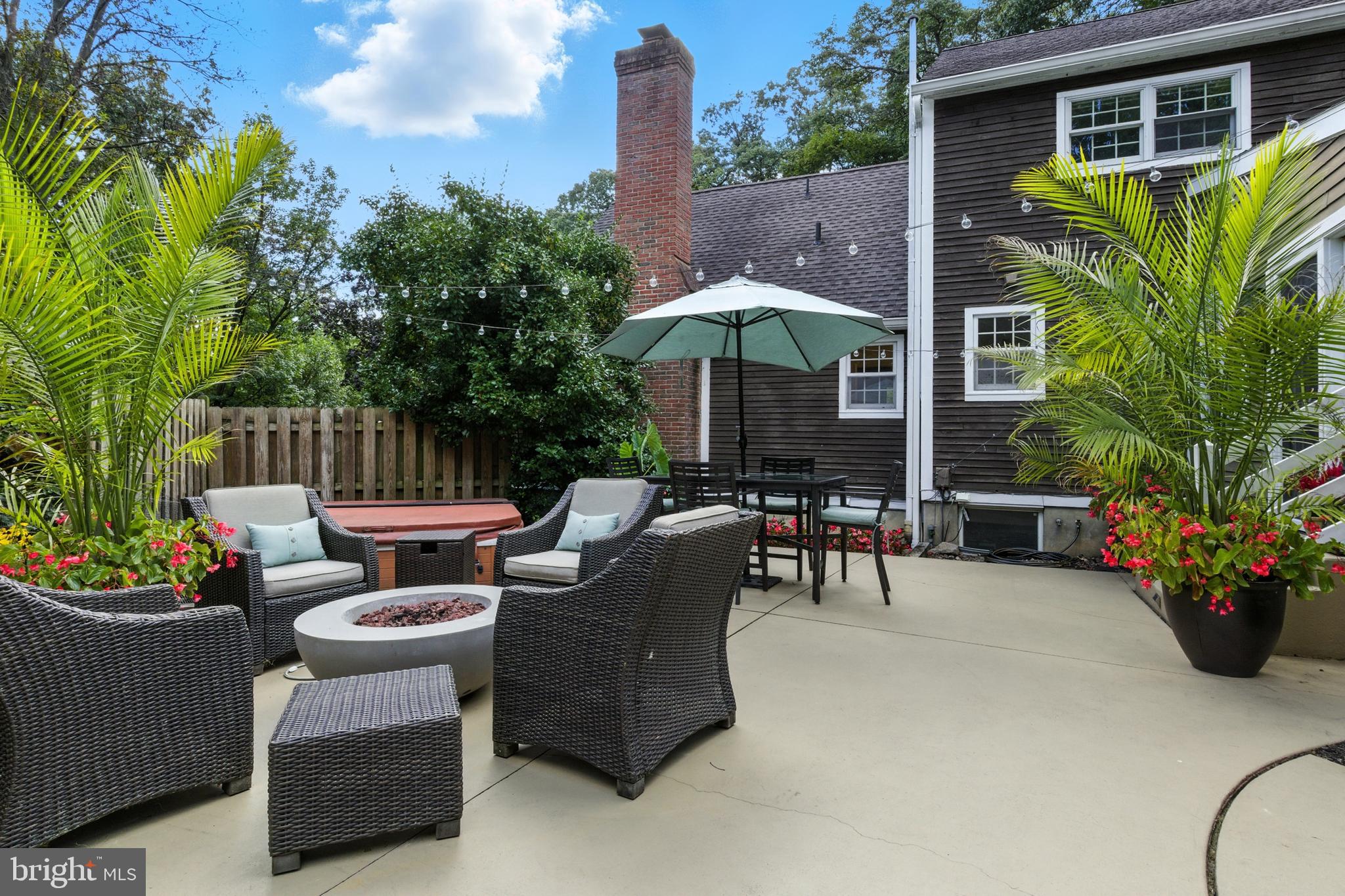 1979 Alcott Road York, PA 17402 - Photo 97 of 115 a view of a patio with couches table and chairs under an umbrella with a fire pit and potted plants