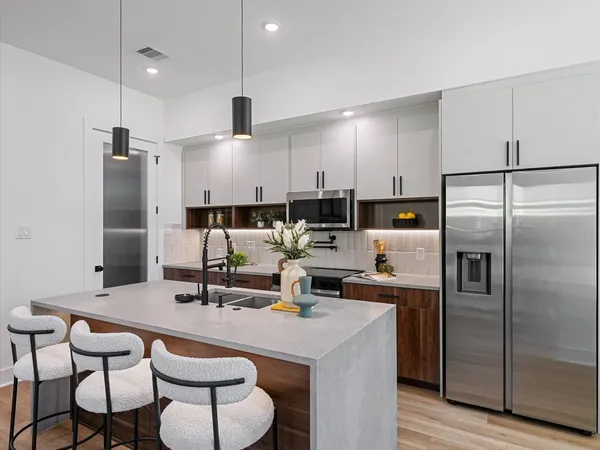a kitchen with kitchen island a white table chairs refrigerator and cabinets