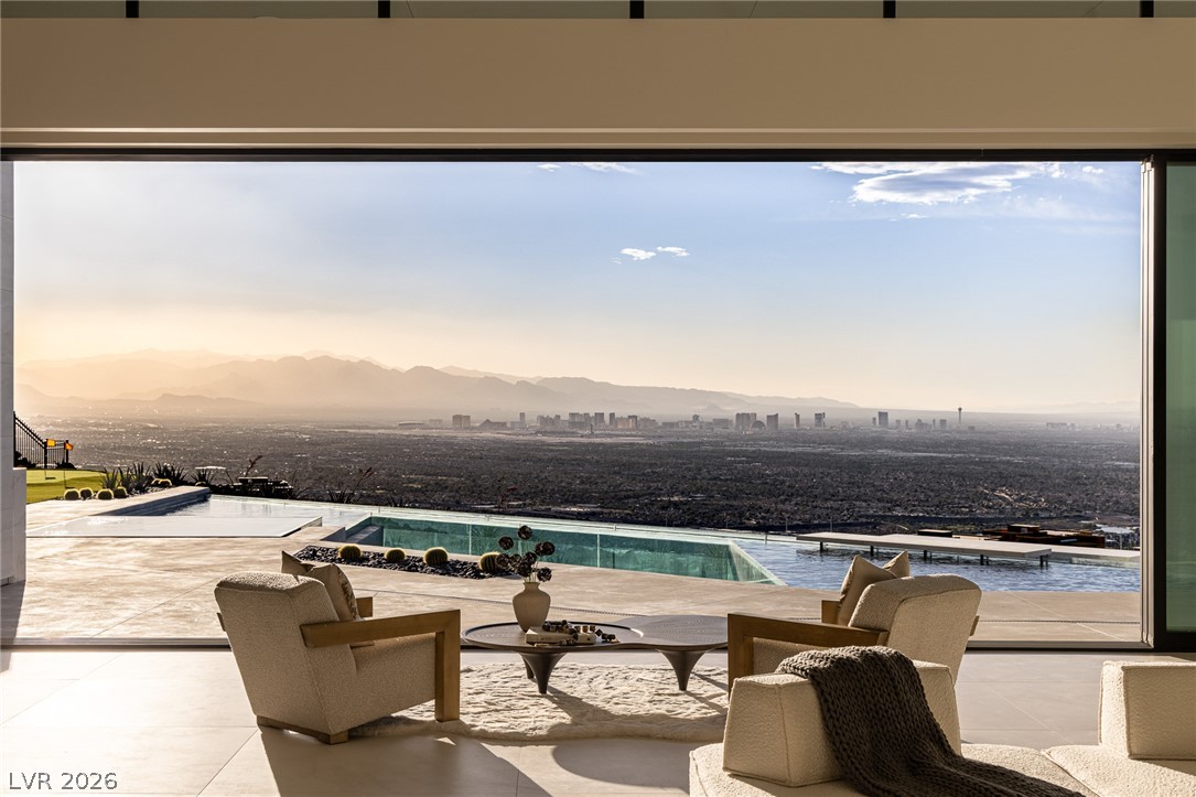 563 Grand Rim Drive Henderson, NV 89012 - Photo 2 of 70 Floor-to-ceiling glass reveals commanding desert and cityscape views from this luxurious living area with a private pool.