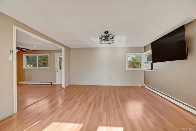 a view of an empty room with window and wooden floor