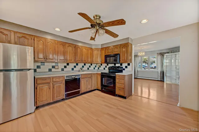 a kitchen with stainless steel appliances granite countertop a refrigerator a sink dishwasher a stove with wooden cabinets and floor