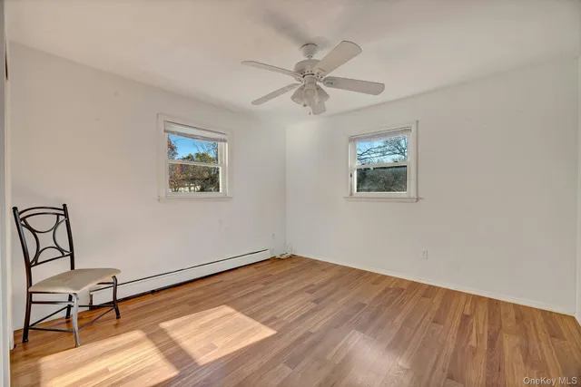 an empty room with wooden floor chandelier fan and windows