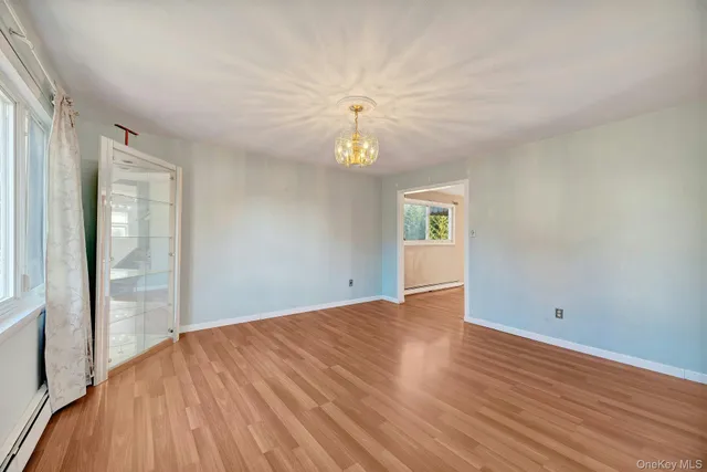 a view of an empty room with window and wooden floor