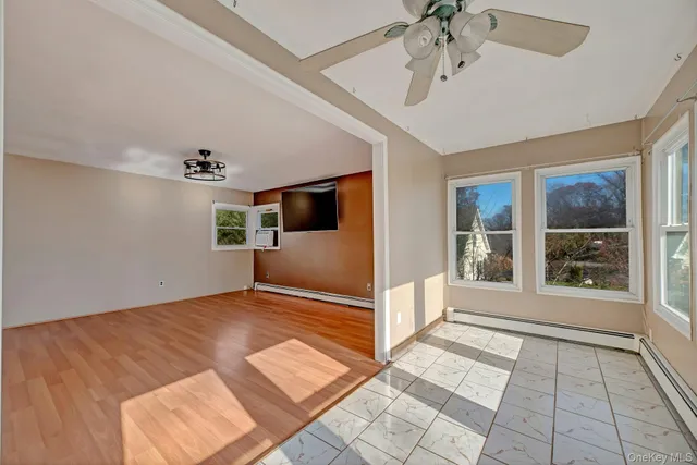 a view of empty room with wooden floor and fan