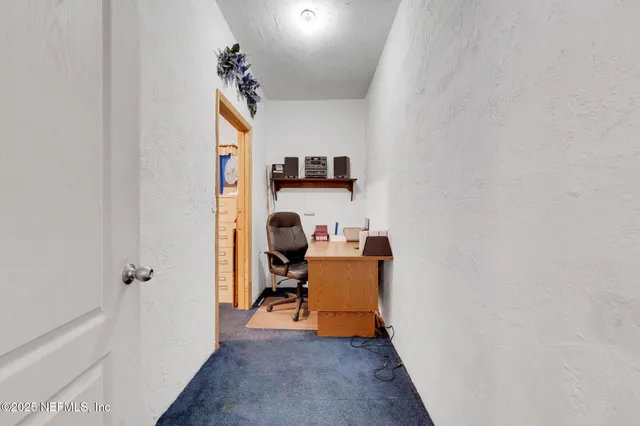 a view of a hallway with workspace and a couch