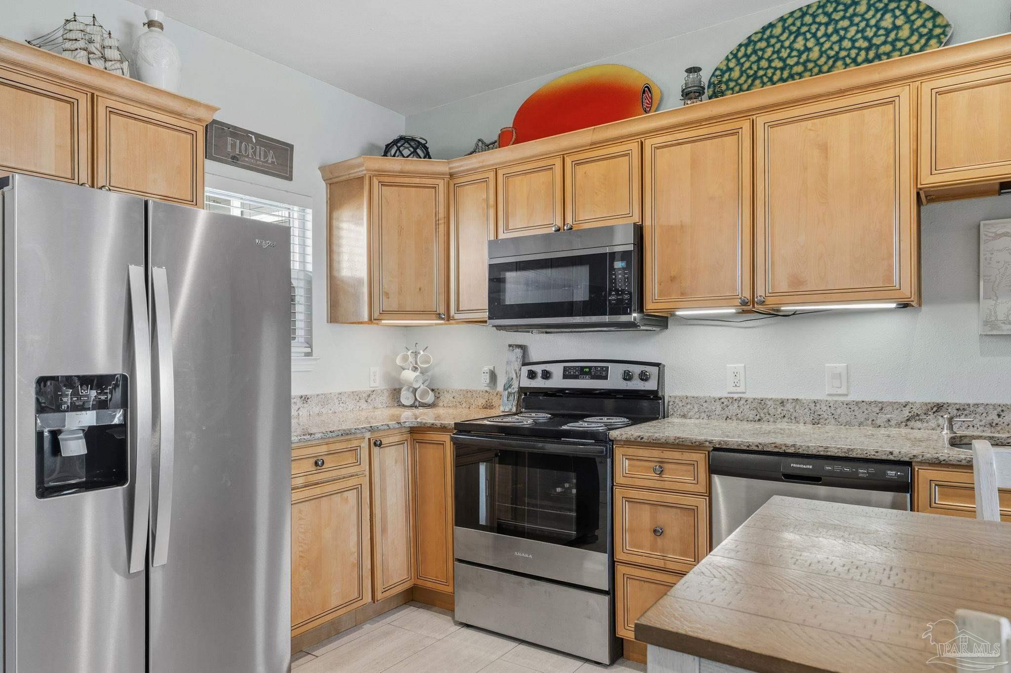 1150 Fort Pickens Road, Unit A3 Pensacola Beach, FL 32561 - Photo 7 of 36 a kitchen with stainless steel appliances granite countertop a refrigerator stove and microwave
