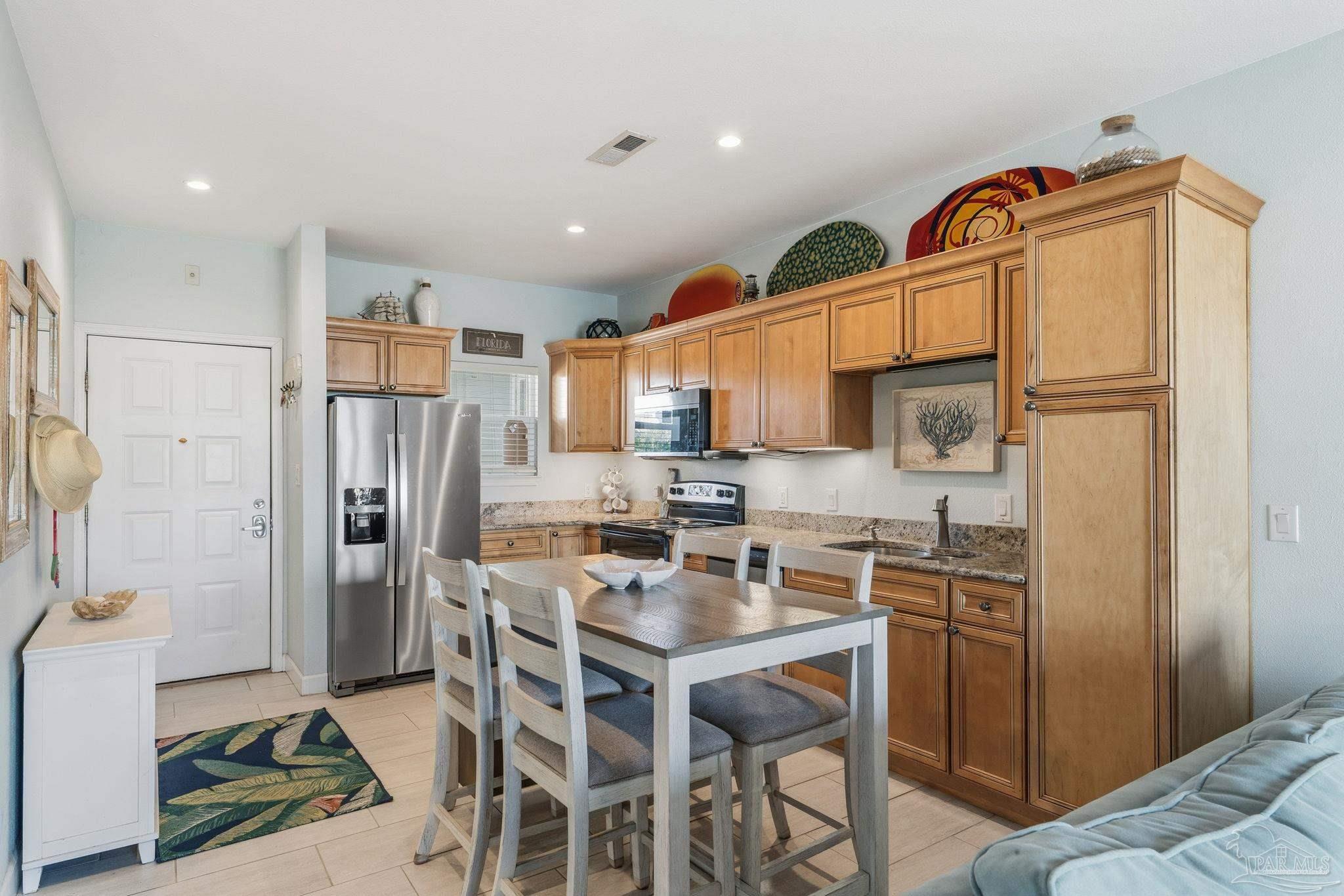 1150 Fort Pickens Road, Unit A3 Pensacola Beach, FL 32561 - Photo 9 of 36 a kitchen that has a refrigerator a sink a stove and chairs with wooden floor