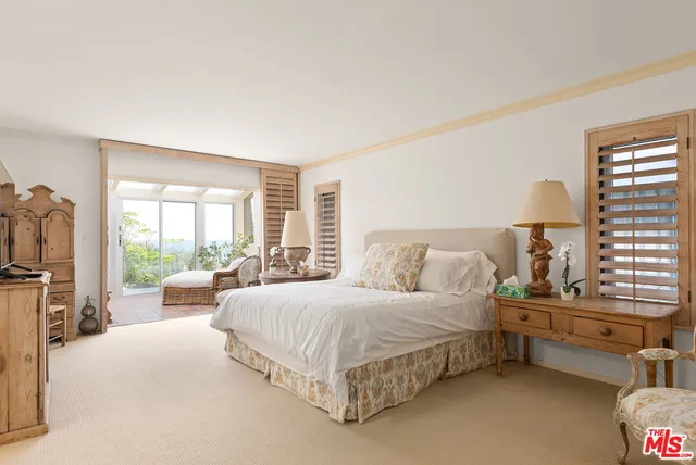 a bedroom with a bed couch and a large window