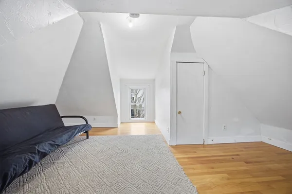 a view of a bedroom with wooden floor and lounge chair