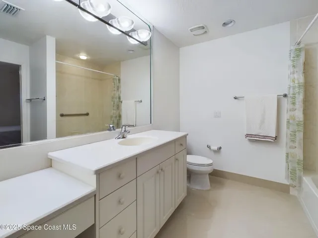 a bathroom with a double vanity sink and mirror with toilet