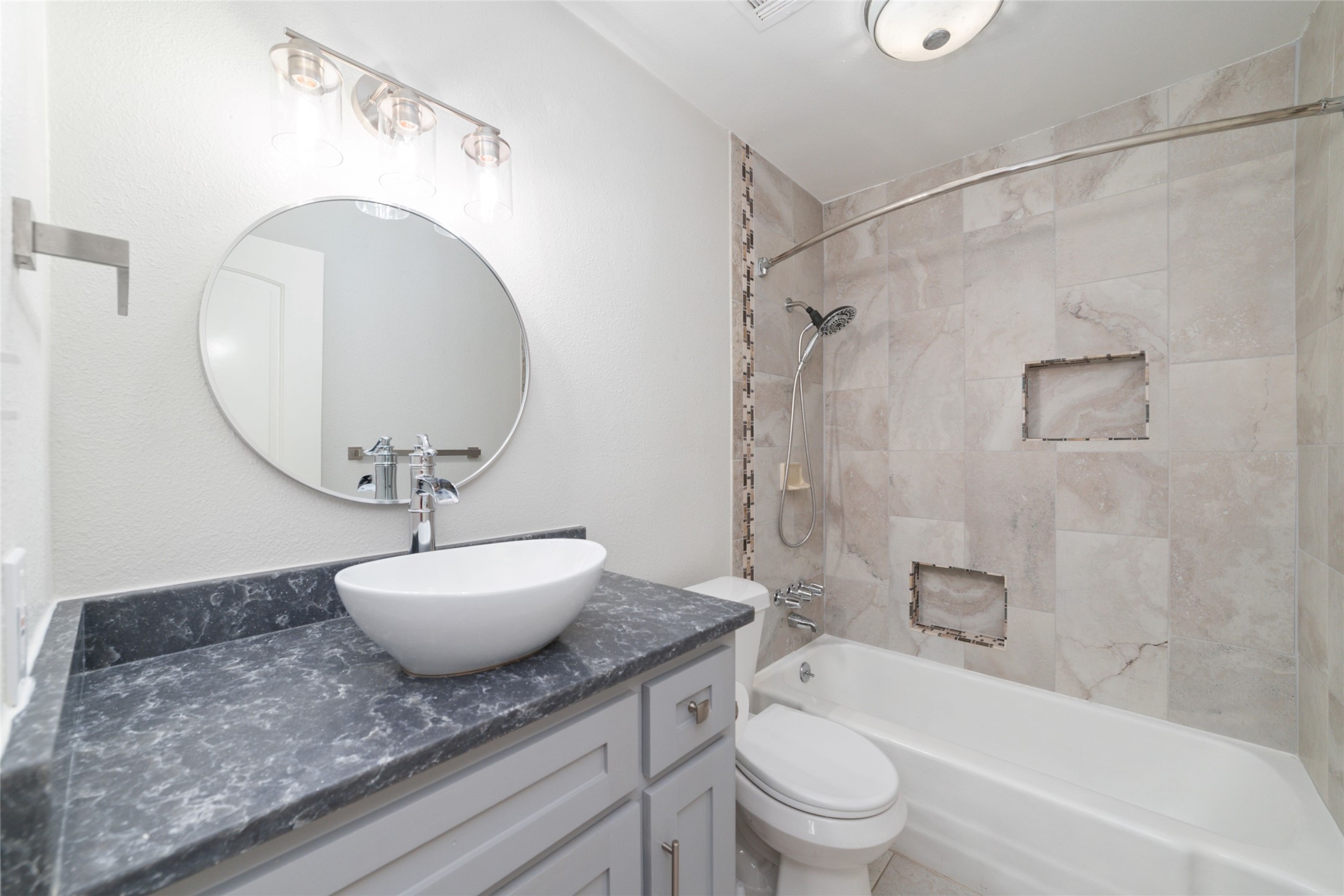 5922 Hummingbird Street Houston, TX 77096 - Photo 23 of 26 The guest bathroom has been beautifully renovated with custom tilework, built-in shelving, and timeless finishes. Every space in this home has been thoughtfully updated with care and attention to detail.