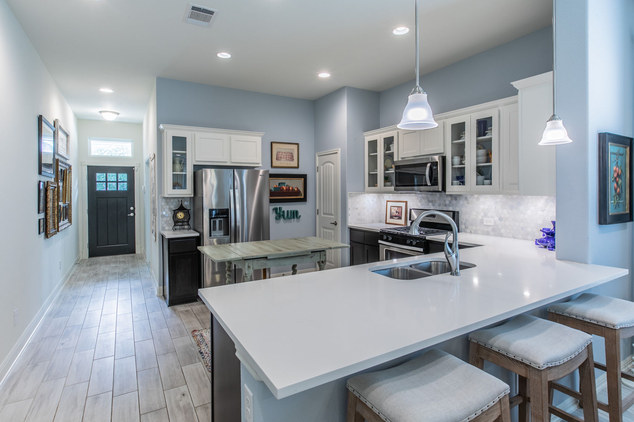 231 Simon Kyle, TX 78640 - Photo 2 of 29 Modern kitchen featuring white cabinetry, stainless steel appliances, and a light-toned countertop with an integrated sink