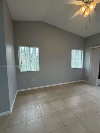 an empty room with windows and chandelier fan