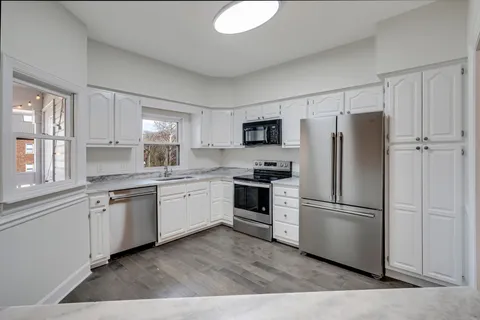a kitchen with cabinets appliances a sink and a window