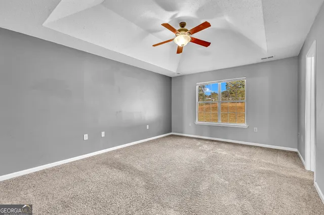 an empty room with a window and a ceiling fan