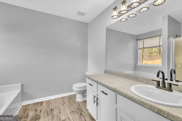 a bathroom with a granite countertop sink a toilet and a mirror