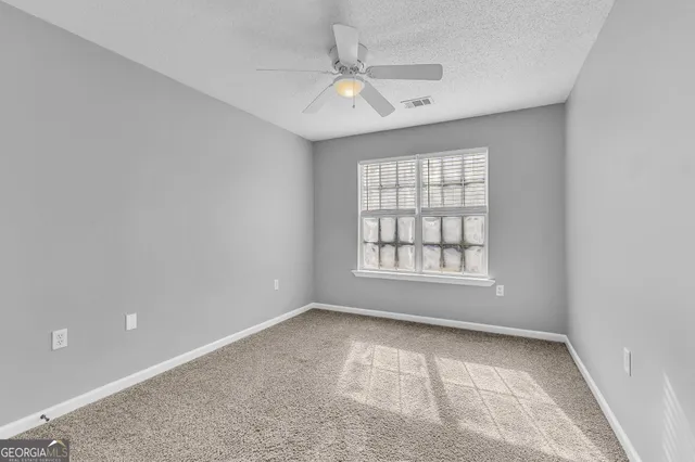 an empty room with a window and a ceiling fan