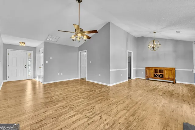 a view of an empty room with window and wooden floor