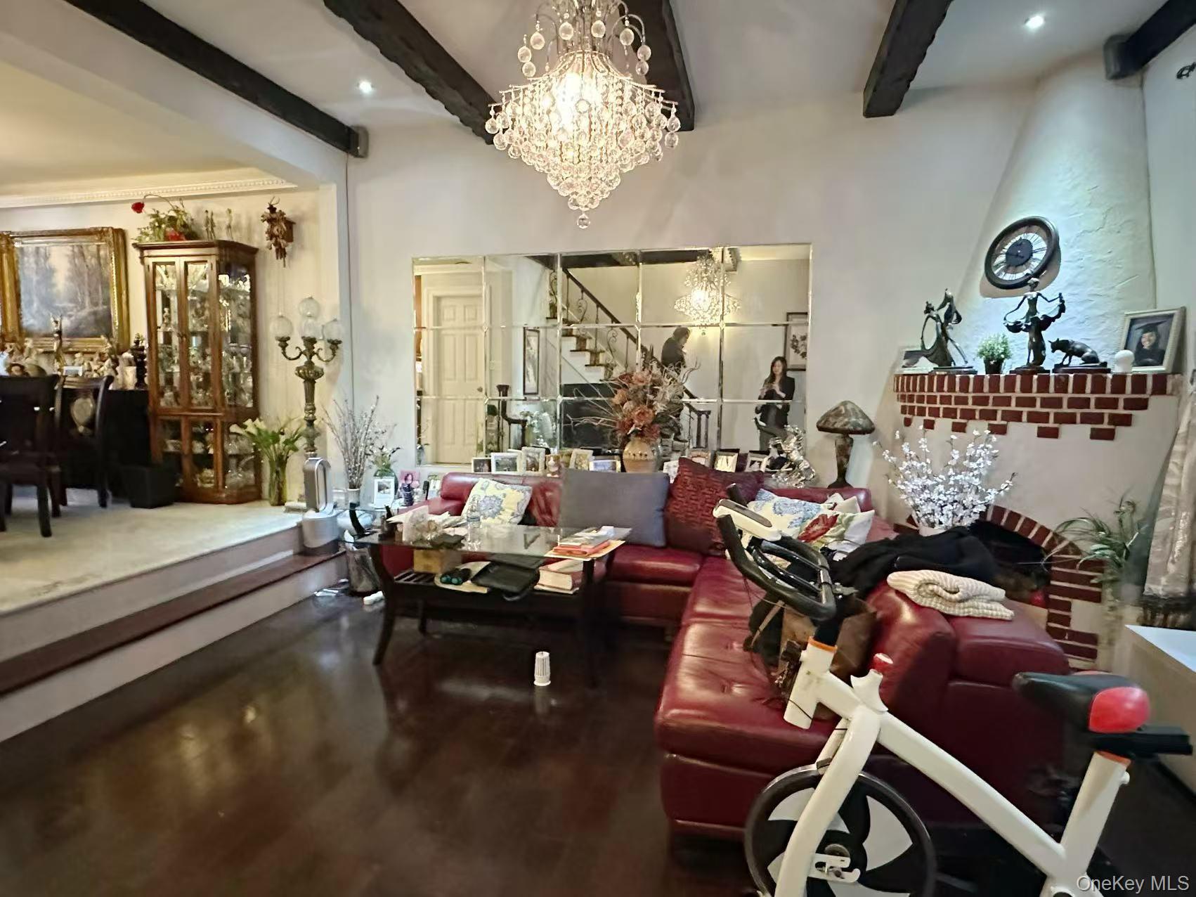 28-07 172nd Street Queens, NY 11358 - Photo 2 of 10 Living area featuring beam ceiling, wood finished floors, stairway, and a chandelier