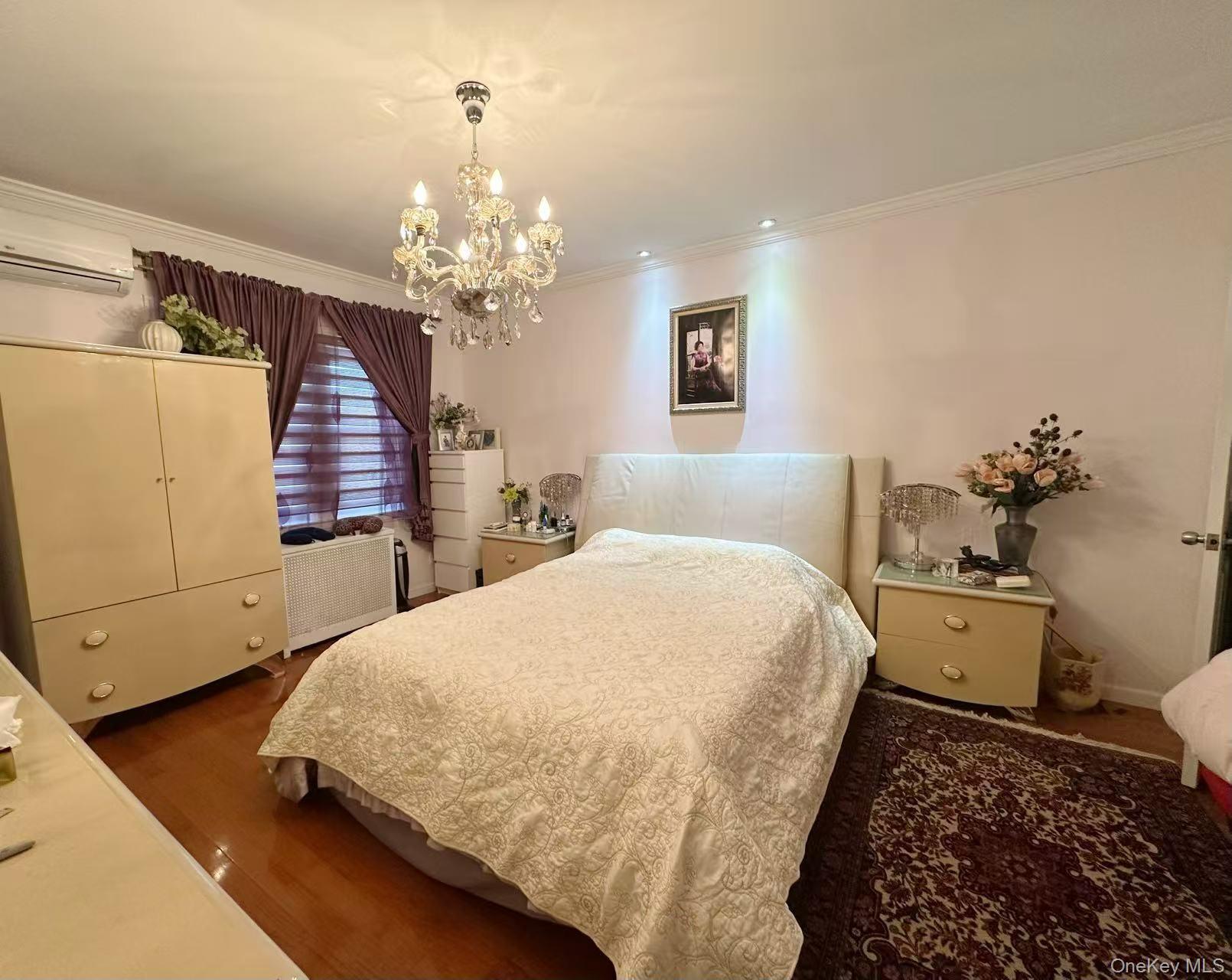 28-07 172nd Street Queens, NY 11358 - Photo 6 of 10 Bedroom with ornamental molding, a chandelier, a wall mounted AC, and dark wood-style flooring