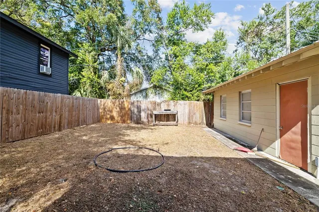 a backyard of a house with wooden fence and large trees