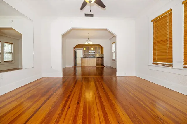 a view of empty room with wooden floor and fan