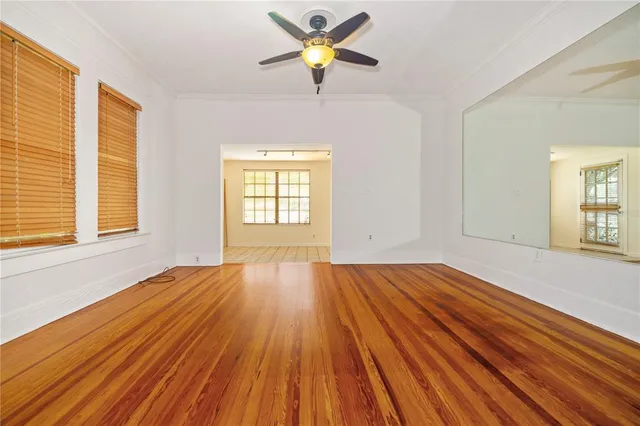 a view of empty room with wooden floor and fan
