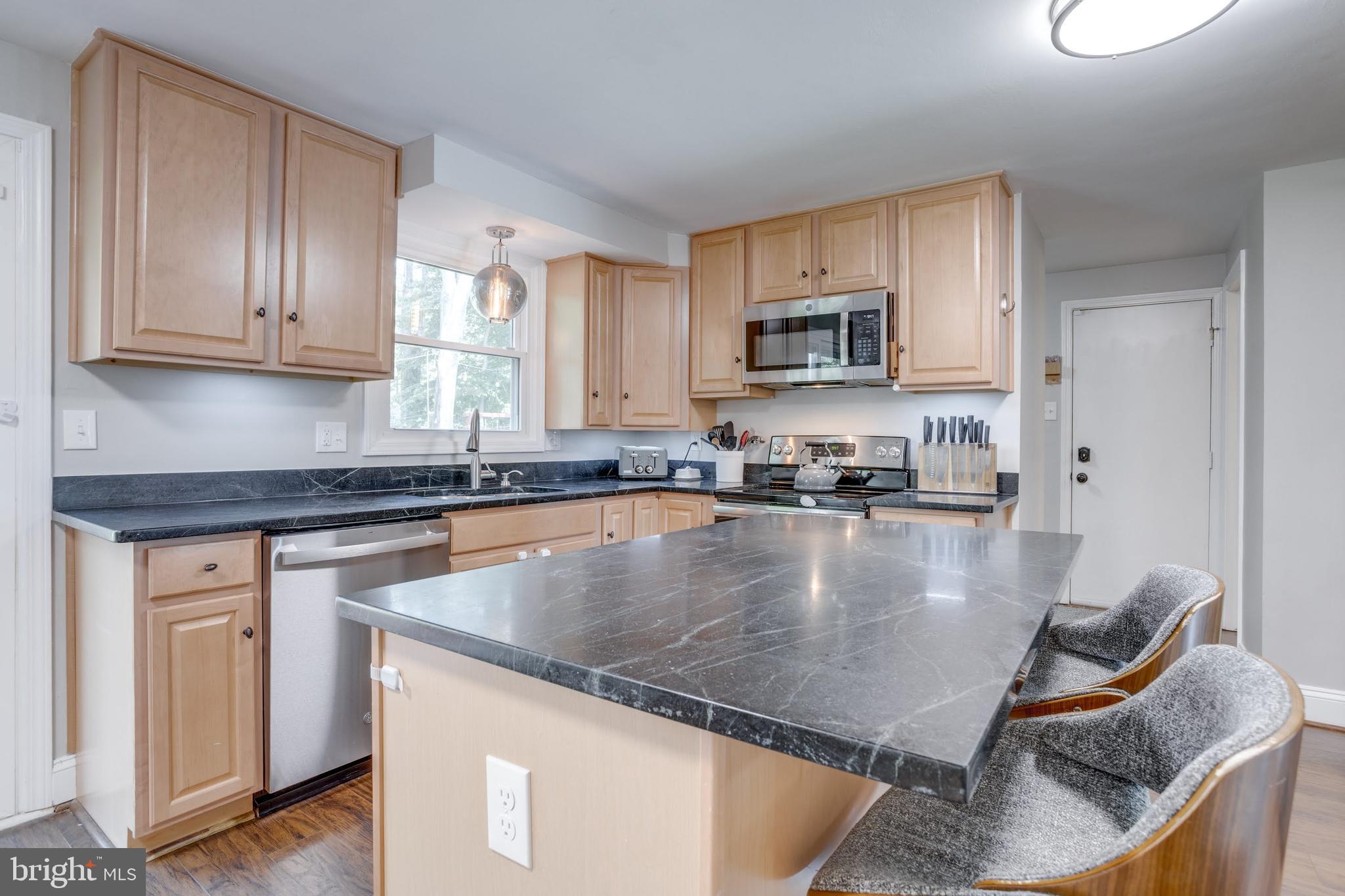 7114 Sterling Grove Drive Springfield, VA 22150 - Photo 20 of 55 a kitchen with stainless steel appliances granite countertop a stove top oven a sink a dining table and chairs with wooden floor