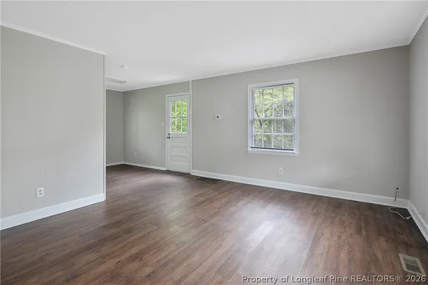 an empty room with wooden floor and windows