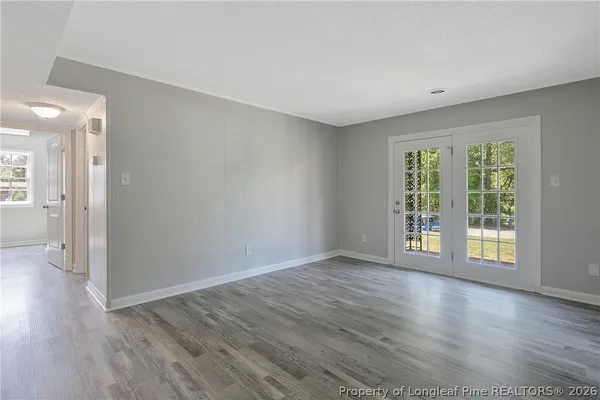 a view of an empty room with wooden floor and a window