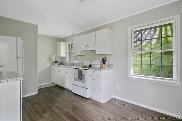 a kitchen with stainless steel appliances a stove top oven a refrigerator a sink and dishwasher with white cabinets