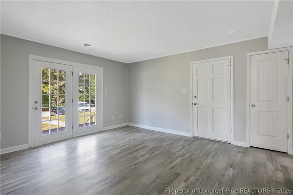 a view of an empty room with wooden floor and a window