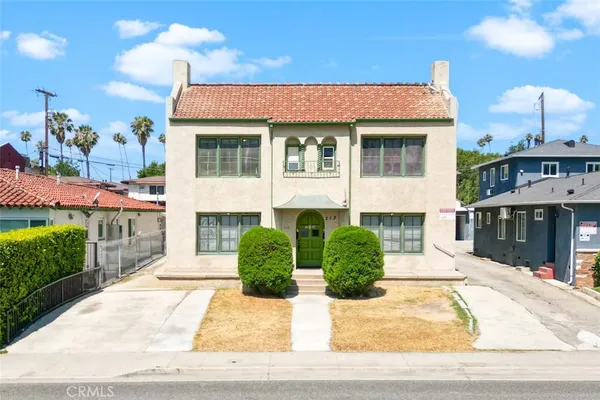 a front view of a house with a yard and potted plants