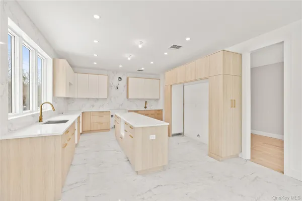 a large kitchen with a sink a counter top space stainless steel appliances cabinets and a sink