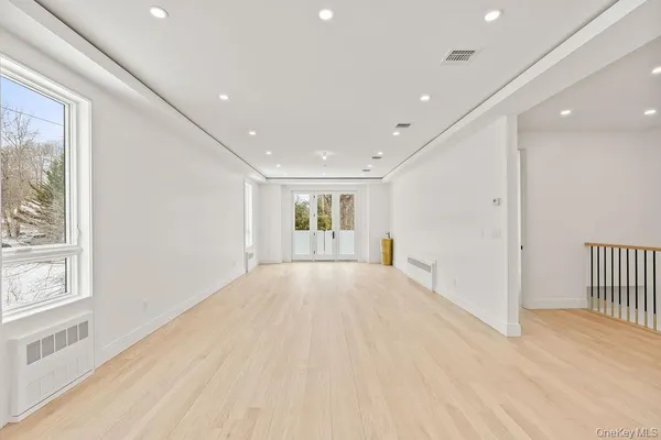 a view of an empty room with wooden floor and windows