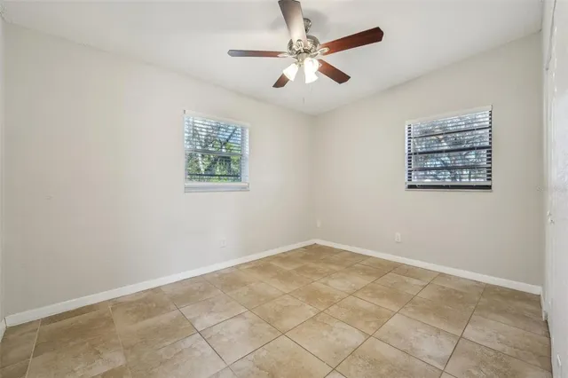 an empty room with windows and fan