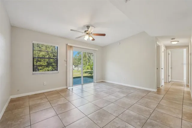 an empty room with chandelier fan and windows