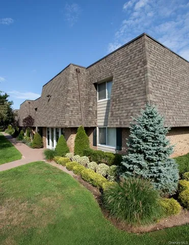 a brick house with a small yard and a large tree