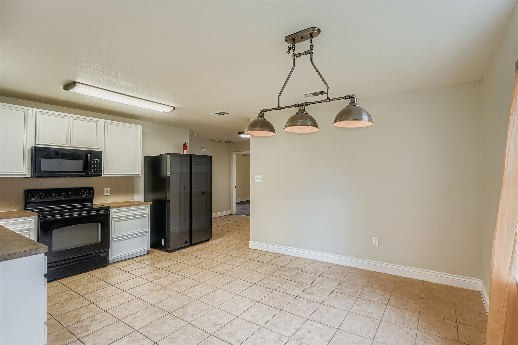 304 South Main Street Elgin, TX 78621 - Photo 15 of 25 Kitchen featuring black appliances, white cabinets, hanging light fixtures, and light tile patterned floors