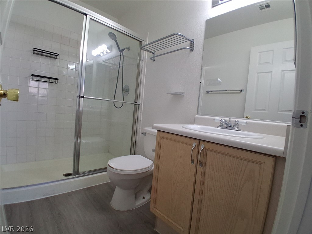 8023 Simone Avenue Las Vegas, NV 89147 - Photo 11 of 12 A compact bathroom offers essential functionality with a vanity, toilet, and shower enclosure.