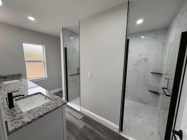 a bathroom with a granite countertop sink a mirror and a shower
