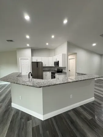 a large kitchen with granite countertop a large counter top and stainless steel appliances