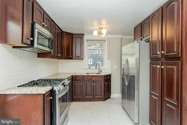 a kitchen with stainless steel appliances granite countertop a refrigerator a sink and wooden cabinets