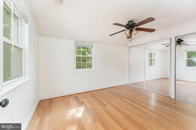 a view of empty room with wooden floor and fan
