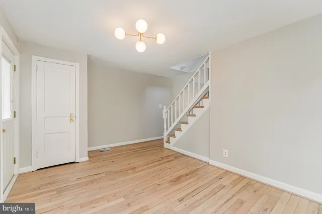 a view of an empty room with wooden floor and staircase