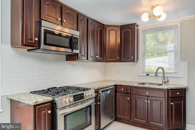 a kitchen with granite countertop stainless steel appliances a stove microwave and sink